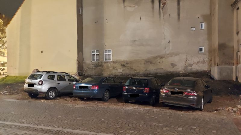 Auta stojące w miejscu rozebranego budynku