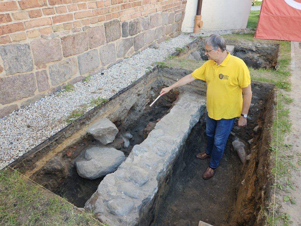 Archeolog Tomasz Janiak, wskazuje na fragmenty ujawnionej konstrukcji